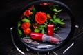 Roses and lipstick are reflected in the mirror. Women`s jewelry on a dark wooden background. Bouquet of flowers and red lipstick Royalty Free Stock Photo
