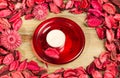 Roses petals on natural wooden table background. Love template for valentines day pink flowers around. Red plate and