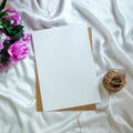 Roses, piece of blank paper (invitation card mockup), and jute cord for knitting on a white cloth Royalty Free Stock Photo