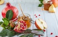Rosh hashanah - jewish New Year holiday concept. Traditional symbols: Honey jar and fresh apples with pomegranate on white wooden Royalty Free Stock Photo