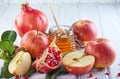 Rosh hashanah - jewish New Year holiday concept. Traditional symbols: Honey jar and fresh apples with pomegranate on white wooden