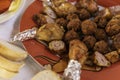 Rosted chicken drumstick and meatballs on a red plate, with tinfoil on drumstick