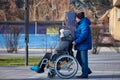 Adult man rolls his disabled mother on wheelchair, careful relationships with disabled person