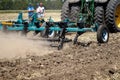 A tractor with a plow is working in the field. Farmers evaluate the efficiency of the plow