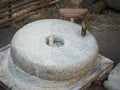 Rotary discoid mill stone for hand-grinding a grain into flour. Medieval hand-driven millstone grinding wheat. The Royalty Free Stock Photo