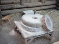 Rotary discoid mill stone for hand-grinding a grain into flour. Medieval hand-driven millstone grinding wheat. The Royalty Free Stock Photo