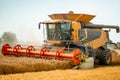 Rotary straw walker cut and threshes ripe wheat grain. Man in combine harvesters with grain header, wide chaff spreader