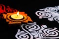 Rotated view of beautiful shining terracotta lamp and red white rangoli design on black background. diwali concept Royalty Free Stock Photo