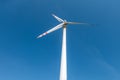 Rotating blades of a windmill propeller on blue sky background. Wind power generation. Pure green energy Royalty Free Stock Photo