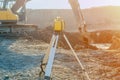 Rotating laser surveying equipment set on construction site with excavator digging foundation in the background.  Laser level as a Royalty Free Stock Photo