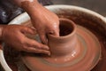 Rotating potter`s wheel and clay ware on it taken from above. A sculpts his hands with a clay cup on a potter`s wheel. Royalty Free Stock Photo