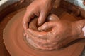 Rotating potter`s wheel and clay ware on it taken from above. A sculpts his hands with a clay cup on a potter`s wheel. Royalty Free Stock Photo