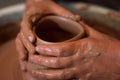 Rotating potter`s wheel and clay ware on it taken from above. A sculpts his hands with a clay cup on a potter`s wheel. Royalty Free Stock Photo