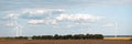 Rotating wind generators in the field against the cloudy sky on sunny summer day.