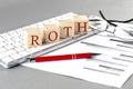 ROTH written on a wooden cube on the keyboard with chart on grey background