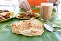Roti canai or paratha served on banana leaf, with mutton curry and fried chicken, and popular teh tarik Royalty Free Stock Photo
