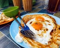 Roti sarang burung, a pratha looks like bird nest with half cook eggs in the middle served with teh tarik as staple breakfast in Royalty Free Stock Photo