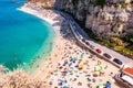 Rotonda beach full of people. Amazing Italian beaches. Sea promenade scenery in Tropea with high cliffs with built on top city