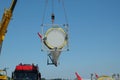 The rotor blade of a windmill is suspended from a crane in the air to be placed next to another rotor blade