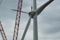 The rotor with rotor blades of the wind turbine is lifted by the high crane, the guy wires are also visibly attached to the rotor