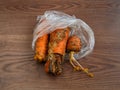 Rotten carrots in bag on brown surface