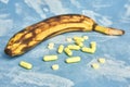 Rotten overripe banana with yellow pills on a blue background. health and pharmacology concept