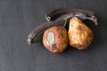 Rotten spoiled rotten fruits, bananas and pears. Black bananas on a black dark background. Damaged products, mold. Copy space for Royalty Free Stock Photo