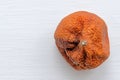 Rotten ugly mandarin on a white background. Orange mandarin with brown stain, top view, closeup. Spoiled product. with place for