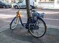 Blue and yellow rental bicycle parked on the street pavement sidewalk