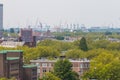 Mixed classic architecture of Rotterdam leafy urban apartment buildings in foreground with harbour waterfront port cranes in backg