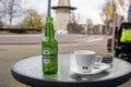 Rotterdam, the Netherlands - March 25, 2023: Heineken beer in a bottle and a cup of coffee on a table in a summer cafe