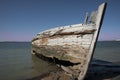 Rotting holed hulk of old wooden fishing boat beached