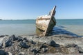 Rotting holed hulk of old wooden fishing boat beached