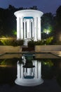 Rotunda and benches on pavement in light lantern at night