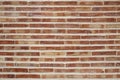 Rough, aged brick wall laid in running bond style, classic one-over-two pattern using narrow, long terracotta bricks