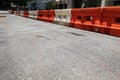 Rough asphalt street with orange and white traffic barricade divider, urban city street scene, creative copy space