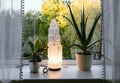 Rough big selenite crystal tower pole lamp illuminated in home on window sill.