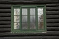 Green window and rough black painted logs on an old log cabin bu Royalty Free Stock Photo