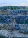 Rough bluish grey stone staircase with grass and sky