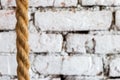 Rough braided rope against the background of a white brick wall in luxury loft interior of a hotel room