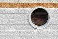Rough cement block wall with gray and red colors with a circular air outlet on the right side. Architecture and design concept