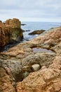 Rough cliff face crags with tide pools and ocean flowing between rocks