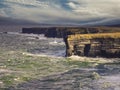 Rough coastline with cliffs and green grass field. Kilkee, county Clare, Ireland. Beautiful Irish nature scenery. Popular travel Royalty Free Stock Photo