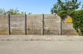 Rough concrete block surrounding wall with empty signboard and ivy on the right. Cement sidewalk and asphalt road in front. Royalty Free Stock Photo