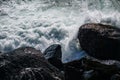 Rough foamy waves break on the black coastal rocks Royalty Free Stock Photo