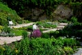 Rough-hewn limestone stones on the paving of a path in a park above a regularly shaped pond. tralk beds around. gray and brown mix