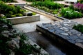 Rough-hewn limestone stones on the paving of a path in a park above a regularly shaped pond. tralk beds around. gray and brown mix