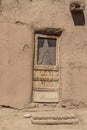 Rough hewn wood door with damaged screen and wooden porch in adobe mud pueblo dwelling in Taos New Mexico