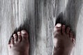 Rough male feet with untreated cuticles and hairy toes stand on a wooden floor