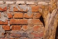 Rough old crumbling orange brickwork. A wall of old broken red bricks and gray cement. dried log stump without bark in the Royalty Free Stock Photo